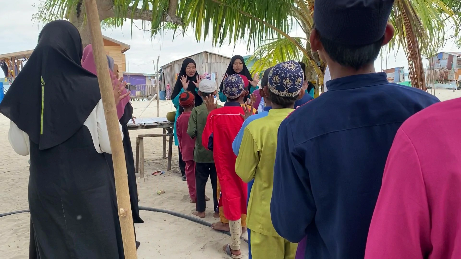 Guru wanita mengajar anak-anak pulau dalam aktiviti luar kelas di kawasan pedalaman Sabah.